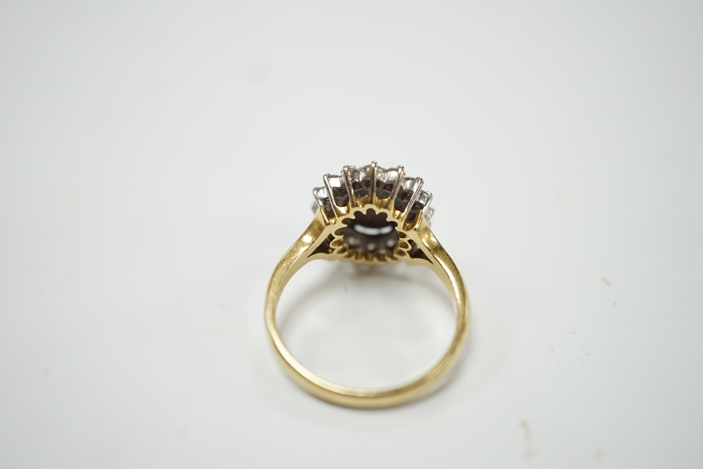 An 18ct, black opal and diamond set oval cluster ring, size P/Q, gross weight 5.4 grams. Fair condition.